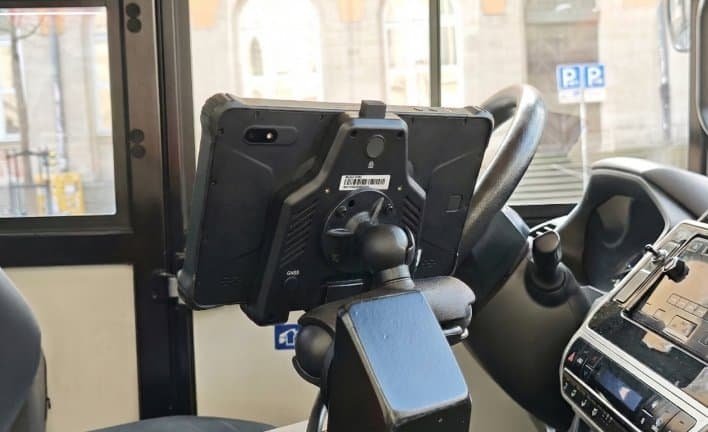 A device mounted on a vehicle dashboard, featuring a rugged tablet or industrial computer secured with a mount, used for navigation, fleet management, or vehicle control systems.